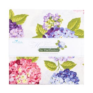 May include: A stack of fabric squares featuring a floral hydrangea design. The fabric has a white background with large, colorful hydrangea blooms in shades of pink, purple, and blue, with green leaves. The text "Hydrangeas In The Garden" is printed on a white label.