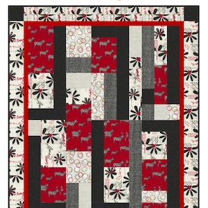 May include: A rectangular quilt featuring a patchwork design with red, black, and cream fabrics. Patterns include zebras, stylized flowers, and circles. The border is cream with black floral motifs, framed by a red inner border and black edges.