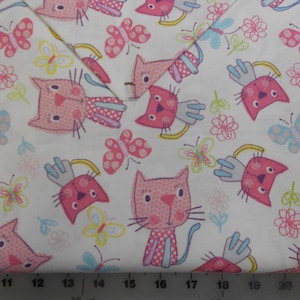 May include: White fabric with a pink and white cat and butterfly pattern. The fabric is 22 inches wide.