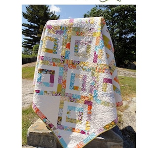 May include: A colourful quilt pattern called "Iphigene's Walk" made with a jelly roll of fabric. The quilt is white with squares of various colours and patterns, including yellow, orange, pink, purple, blue, and green.