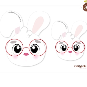 May include: White cookie cutter featuring two cartoon bunny faces wearing red glasses. The bunnies have pink noses and ears. The text "Nerd Bunny Cookie Cutter" is above the bunnies. The cookie cutter is for making cookies.