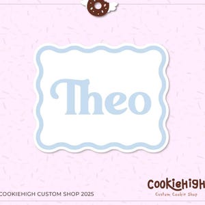 May include: A light blue name tag with the name "Theo" in a playful font, set within a white, scalloped-edge frame. A donut with angel wings and a halo sits at the top. The Cookiehigh Custom Shop logo is at the bottom.