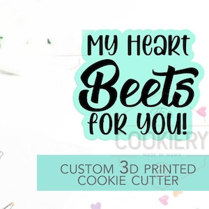 May include: A custom 3D printed cookie cutter with the text "My Heart Beets For You!" in black on a light blue background. The words "Custom 3D Printed Cookie Cutter" are also visible.
