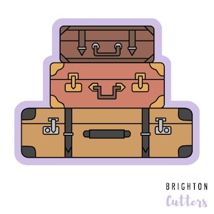 May include: A stack of three vintage-style suitcases in shades of brown and tan, with black accents and metal clasps. The suitcases are arranged from smallest to largest, with a purple outline and the text "BRIGHTON Cutters".