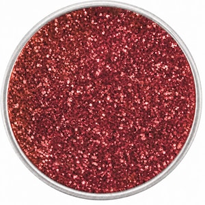 May include: A circular container filled with fine, vibrant red glitter. The container features a simple, thin silver-toned metal rim that frames the densely packed, reflective red particles, creating a uniform and highly textured surface appearance.