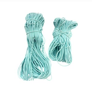 May include: Two bundles of light blue elastic cord, tightly wrapped and secured. The cords are a soft, pastel color, and the bundles are arranged against a white background. The cords are likely for crafting or jewelry making.