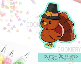 May include: A custom 3D printed cookie cutter in the shape of a cartoon turkey wearing a pilgrim hat. The turkey is brown with a red wattle and a fan of brown feathers. The text "CUSTOM 3D PRINTED COOKIE CUTTER" is below the turkey.