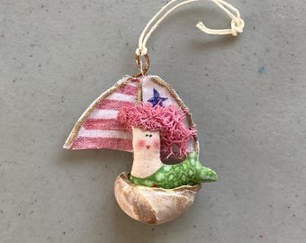 Adorno de velero con forma de pequeña sirena en una concha