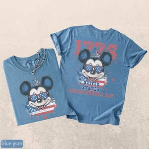 Puede incluir: Dos camisetas vaqueras azules con un gr&aacute;fico de Mickey Mouse con gafas de sol con un dise&ntilde;o patri&oacute;tico. Una camisa tiene un collar de cadena. Las camisetas tienen el texto "1776" y "United States Independence Day".