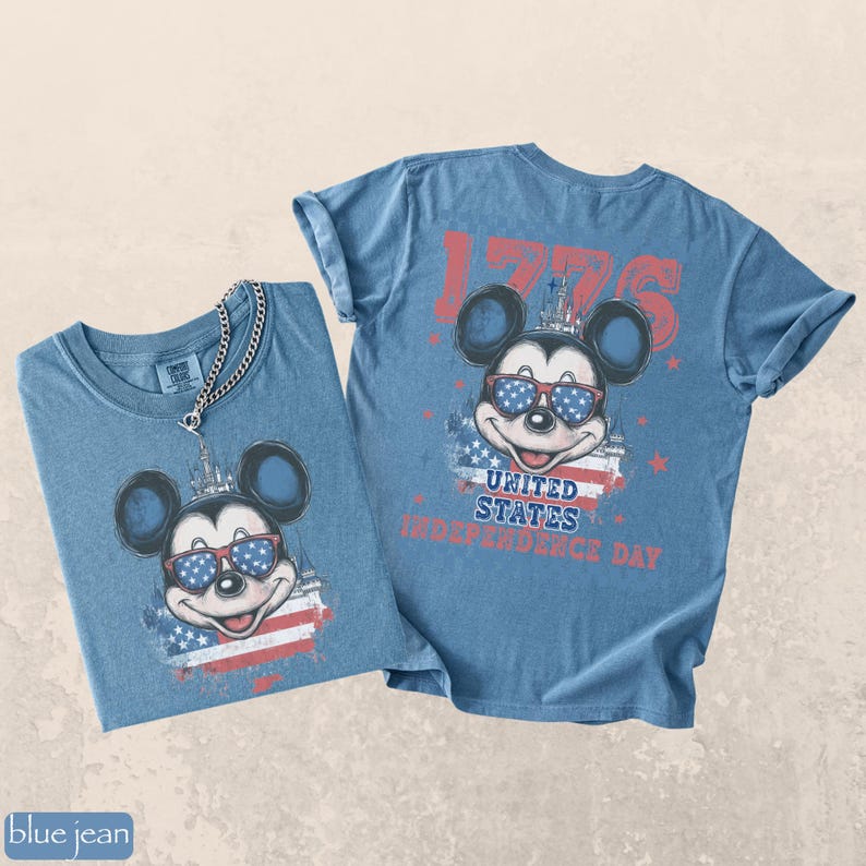 Puede incluir: Dos camisetas vaqueras azules con un gr&aacute;fico de Mickey Mouse con gafas de sol con un dise&ntilde;o patri&oacute;tico. Una camisa tiene un collar de cadena. Las camisetas tienen el texto "1776" y "United States Independence Day".