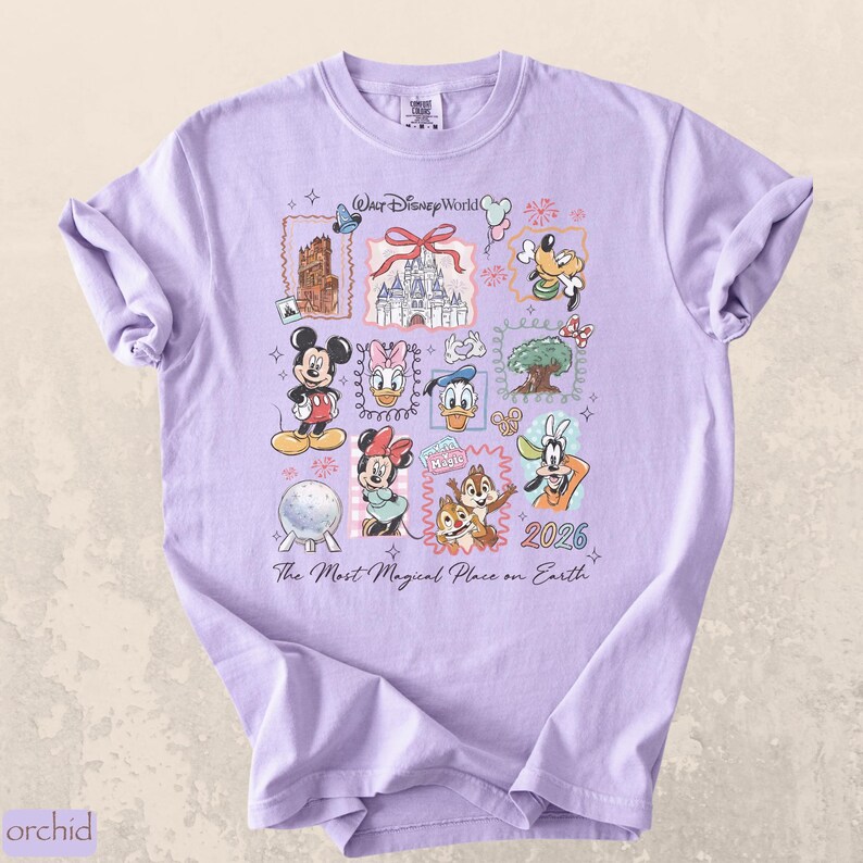 Op de afbeelding: Een lichtpaars t-shirt met een kleurrijk grafisch ontwerp met Disney-personages en bezienswaardigheden. Het ontwerp bevat Mickey Mouse, Minnie Mouse, Donald Duck en Goofy, samen met de tekst "Walt Disney World" en "2026".