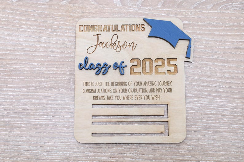 May include: Wooden graduation card with a blue graduation cap, the text "Congratulations Jackson class of 2025" and the message "This is just the beginning of your amazing journey Congratulations on your graduation, and may your dreams take you where ever you wish".