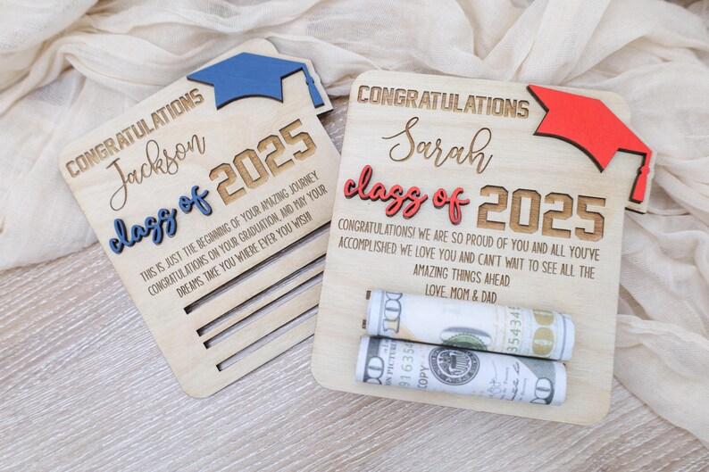 May include: Two wooden graduation signs with a blue and red graduation cap on each. The signs say "Congratulations Jackson class of 2025" and "Congratulations Sarah class of 2025". The signs have a slot for money to be inserted.