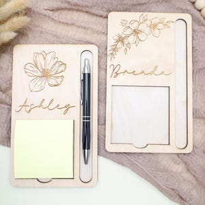 May include: Two wooden notepads with a pen holder, each featuring a floral design and a personalized name. The notepad on the left says "Ashley" and the notepad on the right says "Brenda".