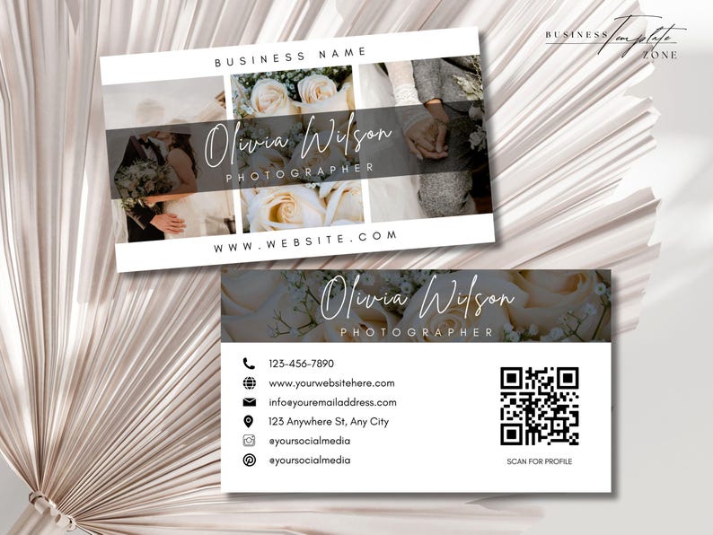 May include: A white business card with a black border and a floral design. The text on the card reads "Olivia Wilson Photographer" and includes contact information, a website address, and a QR code.