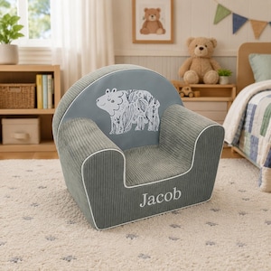May include: A gray corduroy children's armchair with a bear illustration on the backrest. The chair has white piping and the name "Jacob" embroidered on the front. The chair is designed for a child's room.