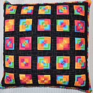 May include: A black pillow with a colorful geometric pattern of squares within squares. The squares are in shades of orange, yellow, green, blue, pink, and red.