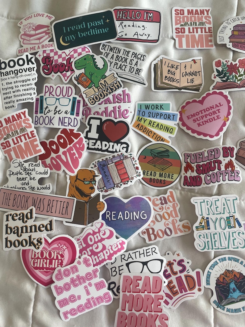 May include: A collection of colorful stickers with book-related themes. The stickers feature phrases like "I read past my bedtime," "Read more books," and "Book Lover." Various designs include books, hearts, and a dinosaur reading.