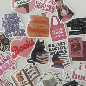 May include: A collection of stickers with book-themed designs. The stickers feature phrases like "book lover," "read more books," and "My job is just books." Various stickers depict stacks of books, open books, and a black cat with books.