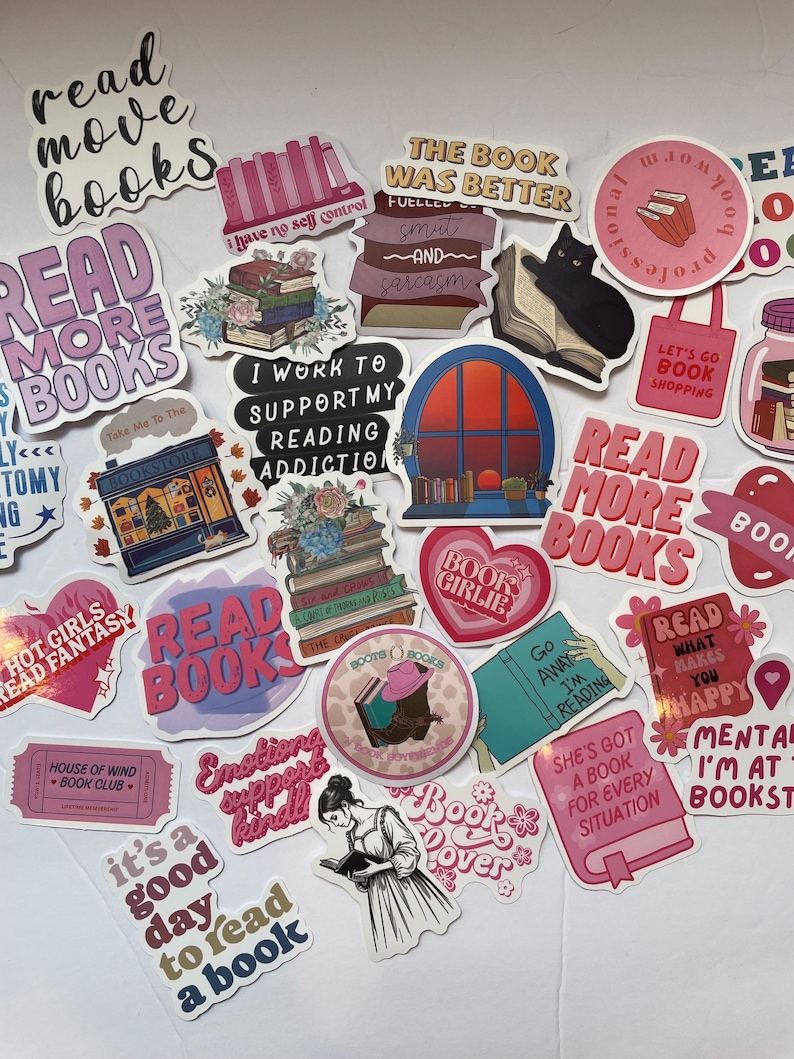 May include: A collection of colorful stickers with book-themed designs and text. The stickers feature phrases like "Read More Books," "Book Lover," and "I Work to Support My Reading Addiction." Various illustrations include stacks of books, a black cat reading, and a bookstore.