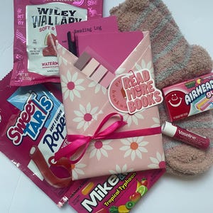 May include: A gift set containing a pink floral envelope with a Read More Books tag, a reading log, a black pen, sticky notes, fuzzy brown socks, a Vaseline lip balm, and various candies including Wiley Wallaby, SweeTarts, Airheads, and Mike and Ike.