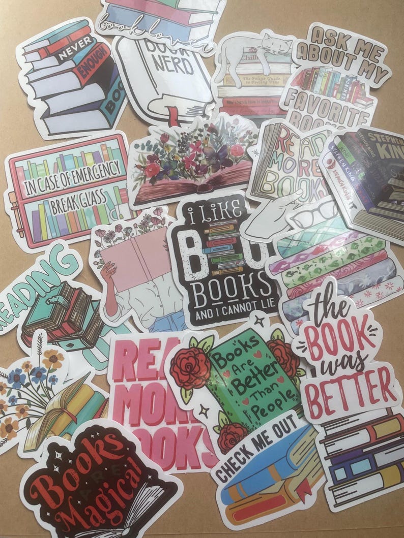 May include: A collection of colorful stickers with book-themed designs. The stickers feature phrases like "Never Enough Books," "Book Nerd," and "I Like Books." Various designs include stacks of books, open books with floral arrangements, and a cat sleeping on books.