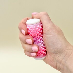 Chunky pink hand roller with deep spikes, silent tactile fidget for grounding.