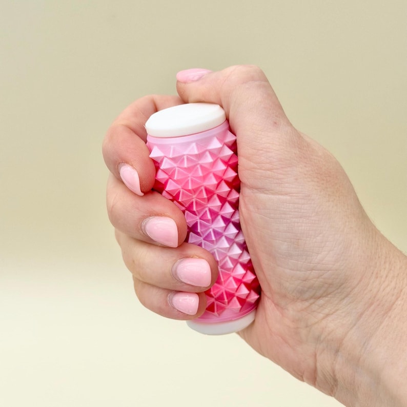 Chunky pink hand roller with deep spikes, silent tactile fidget for grounding.