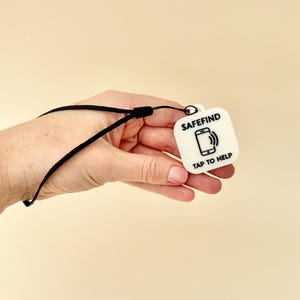 Black NFC tag keyring showing its practical use for quick phone tap access to contact details.