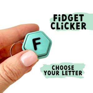 Op de afbeelding: Een tealblauwe fidget clicker in de vorm van een hexagon met de letter "F" in zwart gedrukt. De clicker is bevestigd aan een zilveren sleutelhanger. De tekst "FIDGET CLICKER" en "CHOOSE YOUR LETTER" is in zwart gedrukt op een groene achtergrond.