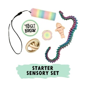 Könnte beinhalten: Eine Sammlung von sensorischen Spielzeugen in Pastellfarben, darunter eine regenbogenfarbene, segmentierte Röhre, eine segmentierte Schlange, ein runder Zappelspielzeug, ein Delfin und ein geflochtener Ball. Das Set enthält ein schwarzes Schlüsselband und einen Aufkleber mit "FIDGET BREAK". Der Text "STARTER SENSORY SET" ist ebenfalls sichtbar.