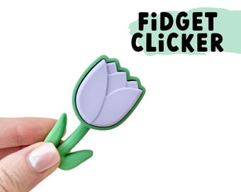 May include: A green and purple tulip-shaped fidget clicker. The clicker is made of silicone and has a soft, squishy texture.