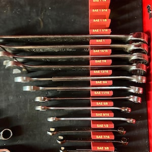 May include: A set of wrenches with SAE sizes ranging from 1/4 inch to 1 5/16 inches, organized in a red toolbox. The wrenches are arranged in order of size, with the smallest wrench at the bottom and the largest wrench at the top.