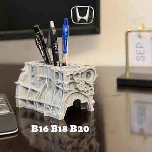 Może przedstawiać: Szary, 3D-drukowany organizer na biurko w kształcie bloku silnika Hondy z trzema długopisami w środku. Organizer jest oznaczony jako "B16 B18 B20".