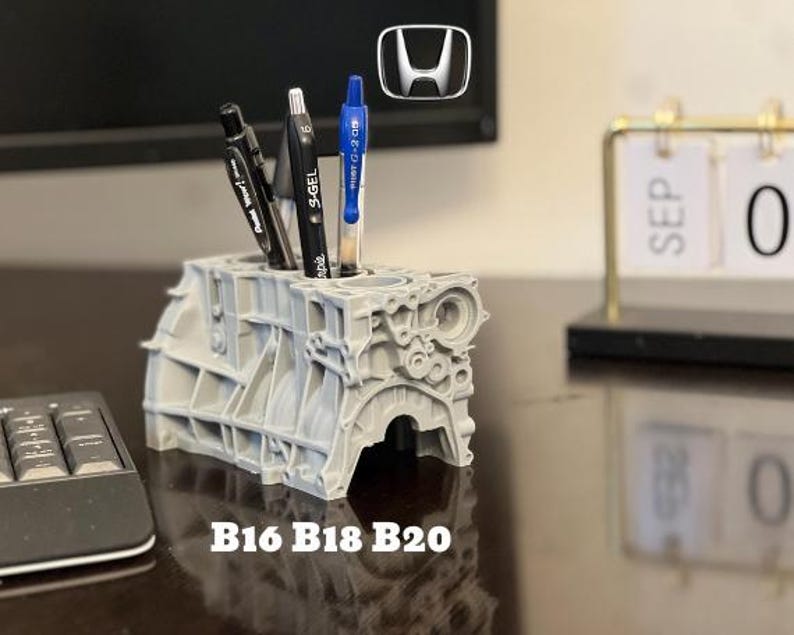 Może przedstawiać: Szary, 3D-drukowany organizer na biurko w kształcie bloku silnika Hondy z trzema długopisami w środku. Organizer jest oznaczony jako "B16 B18 B20".