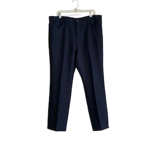 May include: Navy blue pants hanging on a white hanger. The pants have a classic, straight-leg design with front pockets and a button closure. The fabric appears to be a solid, dark blue color.
