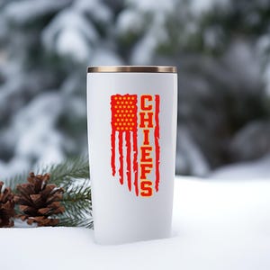 May include: White travel mug featuring a red, white and blue American flag design with the word "CHIEFS" in yellow lettering.
