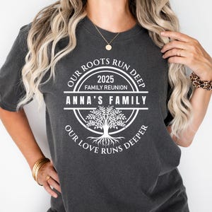 May include: A dark gray t-shirt with a white circle design featuring a tree, the text "Our Roots Run Deep", "2025 Family Reunion", "Anna's Family", and "Our Love Runs Deeper".