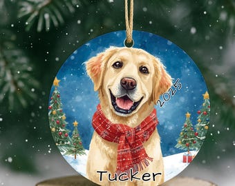 Puede incluir: Adorno navideño redondo con un golden retriever sonriente con una bufanda roja. El adorno tiene un fondo azul con árboles de Navidad y el texto "2025" y "Tucker". Una decoración festiva.