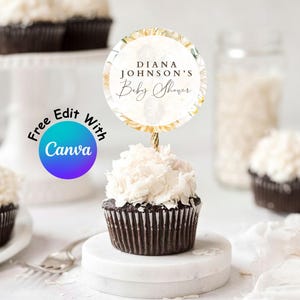 Puede incluir: Un adorno redondo para cupcake con un diseño floral de pétalos amarillos y blancos, que muestra el texto DIANA JOHNSON'S Baby Shower en letras negras, unido a un palillo dorado fino y colocado en un cupcake de chocolate con glaseado blanco.