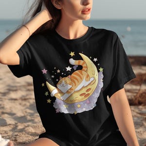 Camiseta con un lindo gato en la luna, camiseta con diseño de luna y estrellas, camiseta adorable para amantes de los gatos, camiseta con gráfico de gato de dibujos animados, camiseta con arte de gato celestial