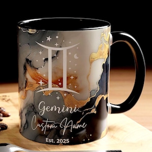 Puede incluir: Una taza de café con asa negra y un diseño veteado en tonos grises, dorados y blancos. La taza presenta el símbolo del zodiaco Géminis, la palabra "Gemini", y el texto "Custom Name" y "Est. 2025".