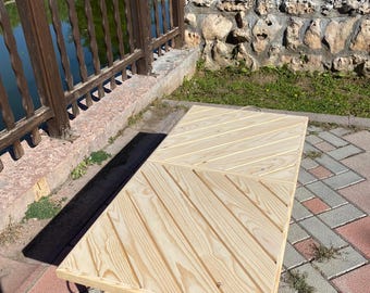 May include: A light-colored wooden coffee table with a geometric design. The tabletop is made of parallel wooden planks arranged in a diagonal pattern. The table has four short, rounded legs and a rope detail.