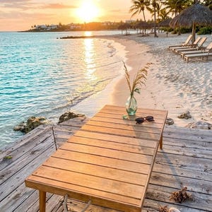 May include: A wooden table with a vase of dried plants and sunglasses sits on a wooden dock. The beach scene includes a sandy shore, turquoise water, palm trees, and a sunset.