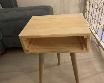 May include: A simple wooden end table with a shelf and four legs. The table is made of natural wood and has a light brown finish.