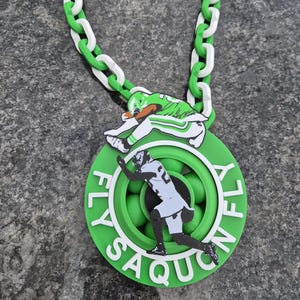 May include: A green and white chain necklace with a circular pendant. The pendant features a football player graphic and the words "FLY SAQUON FLY" in white. The necklace is made of interlocking chain links.