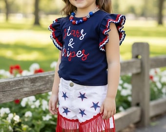 Top azul marino con estampado patriótico de barras y estrellas, shorts vaqueros blancos. OFG50593