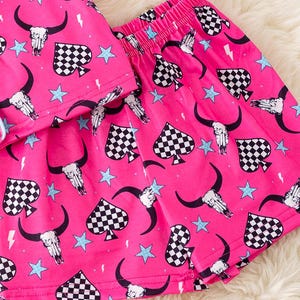Pode incluir: Cal&ccedil;as de pijama rosa com um padr&atilde;o de espadas xadrez, caveira e estrela.