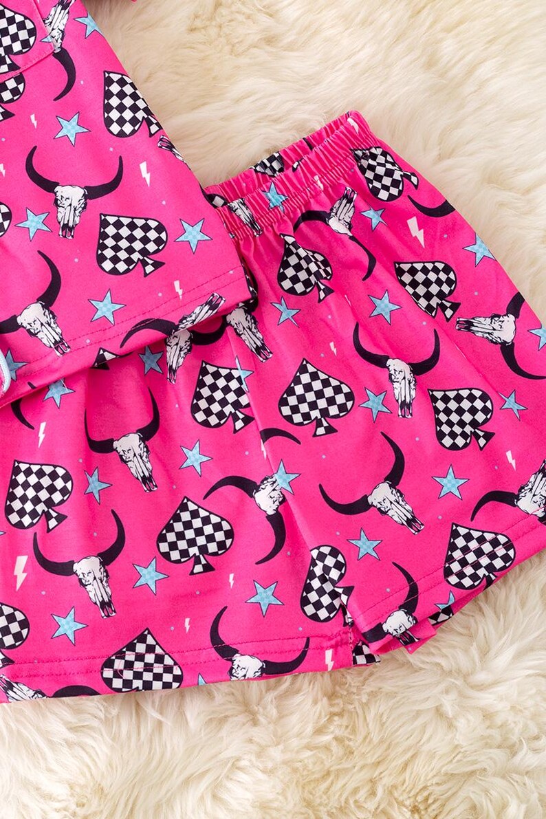 Pode incluir: Cal&ccedil;as de pijama rosa com um padr&atilde;o de espadas xadrez, caveira e estrela.