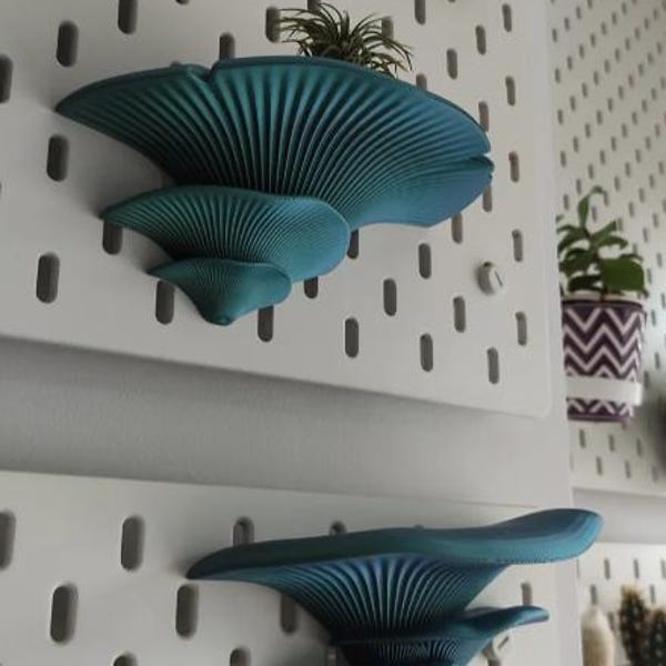 May include: Two teal blue mushroom-shaped wall shelves mounted on a white pegboard wall.
